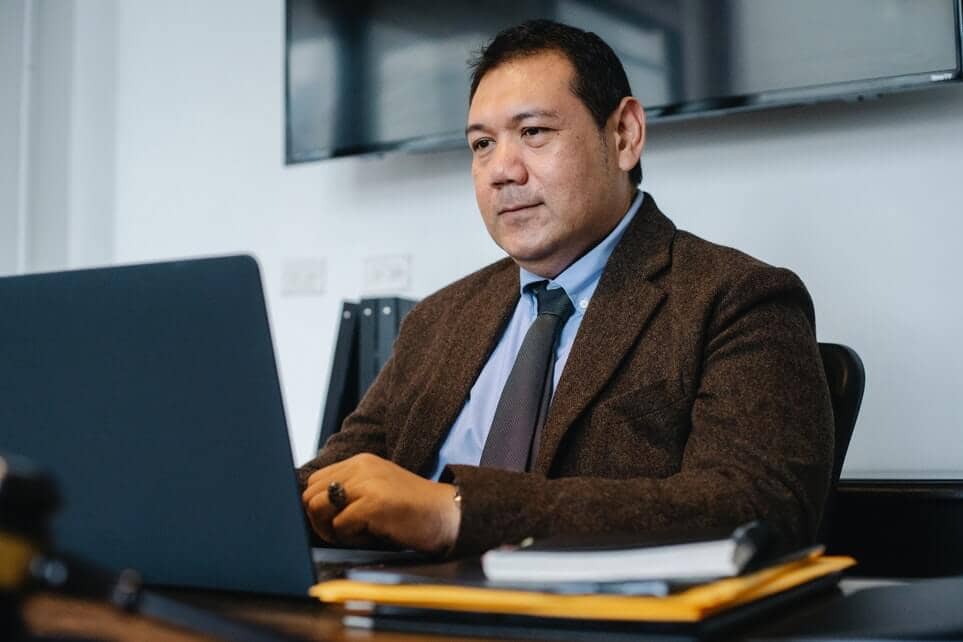 Focused ethnic businessman watching corporate videos while working in office.